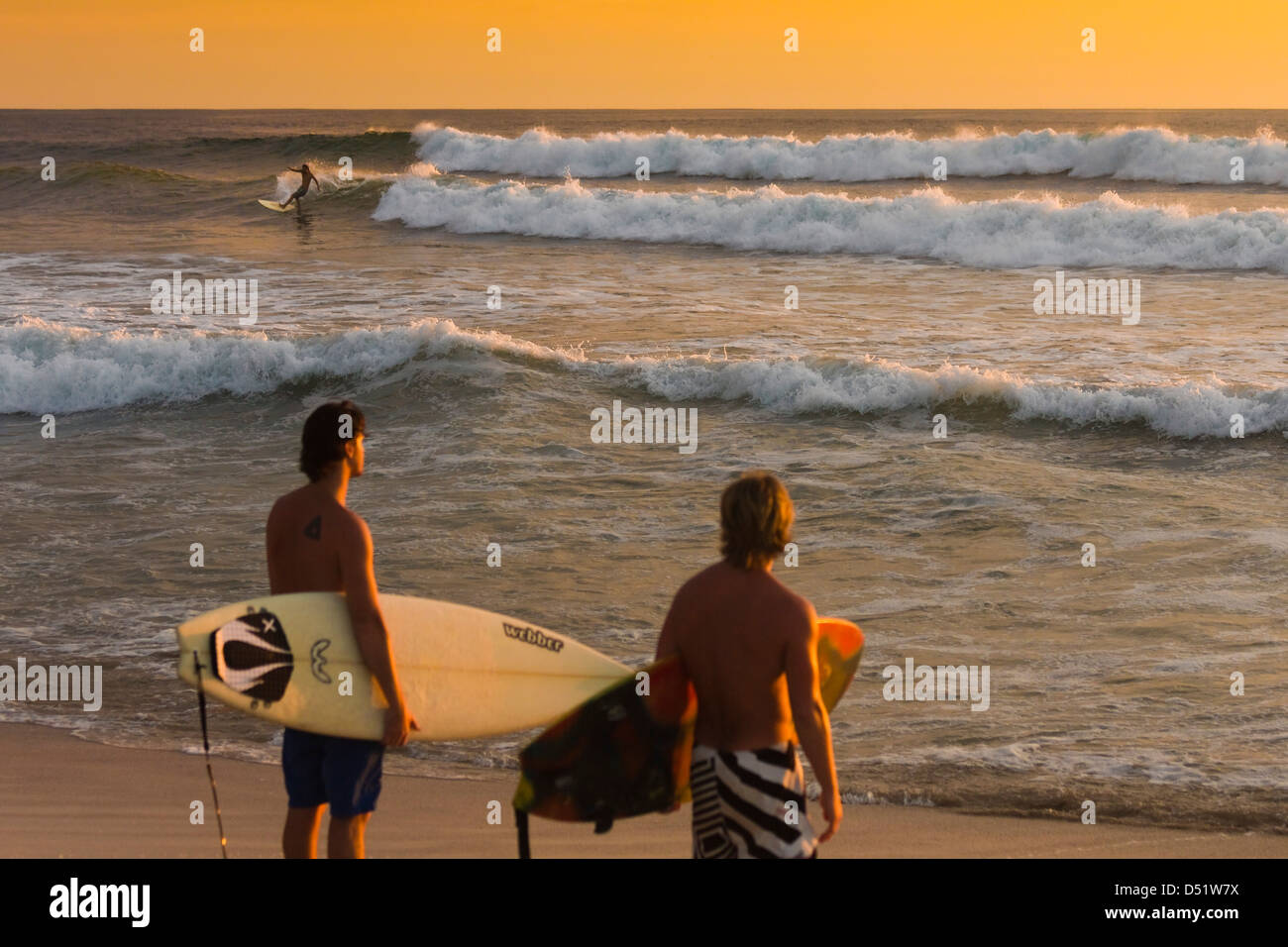 Surfers about to surf at sunset, Playa Guiones beach, Nosara, Nicoya Peninsula, Guanacaste Province, Costa Rica, Central America Stock Photo