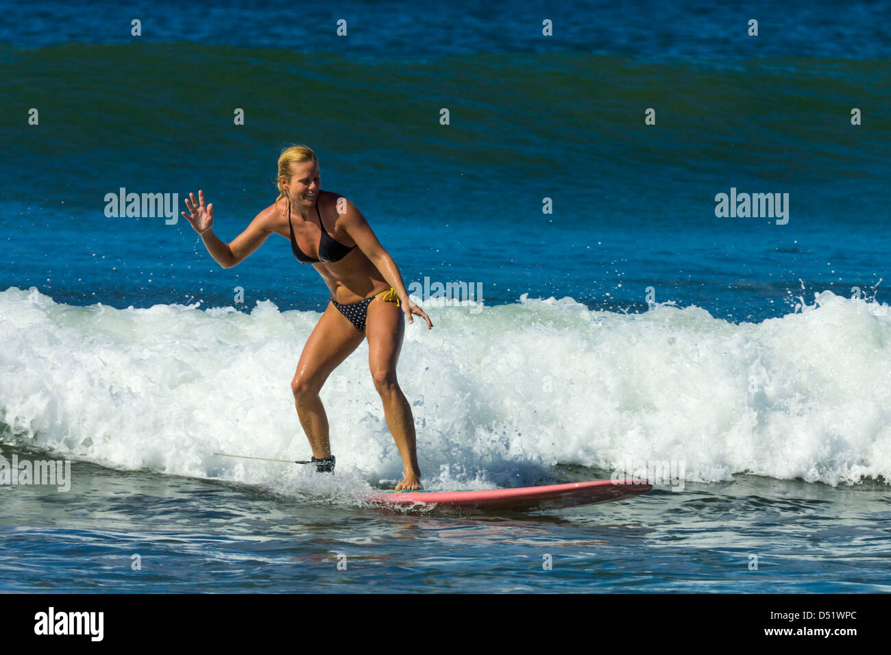 Young woman surfing longboard at Playa Guiones beach, Nosara, Nicoya