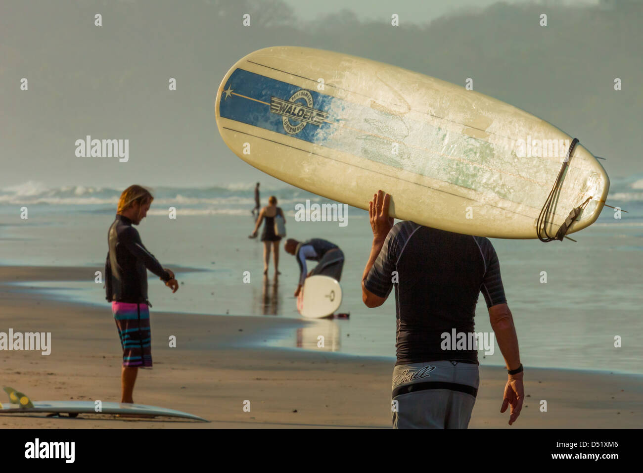 Surfer carrying longboard at popular Playa Guiones surf beach, Nosara