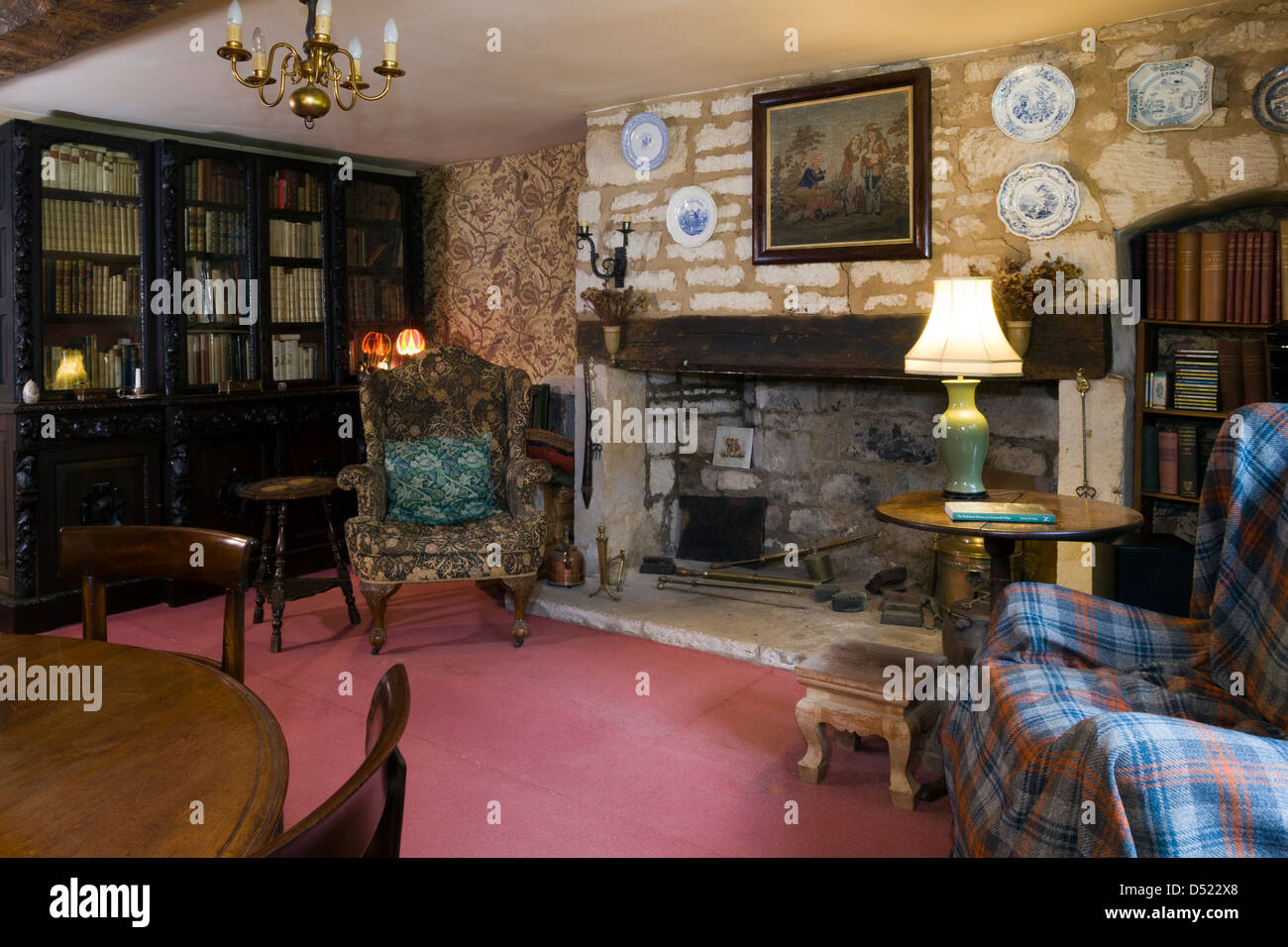 A very traditional cottage sitting room, wing backed chairs, antique funiture and a large unused fireplace. Stock Photo