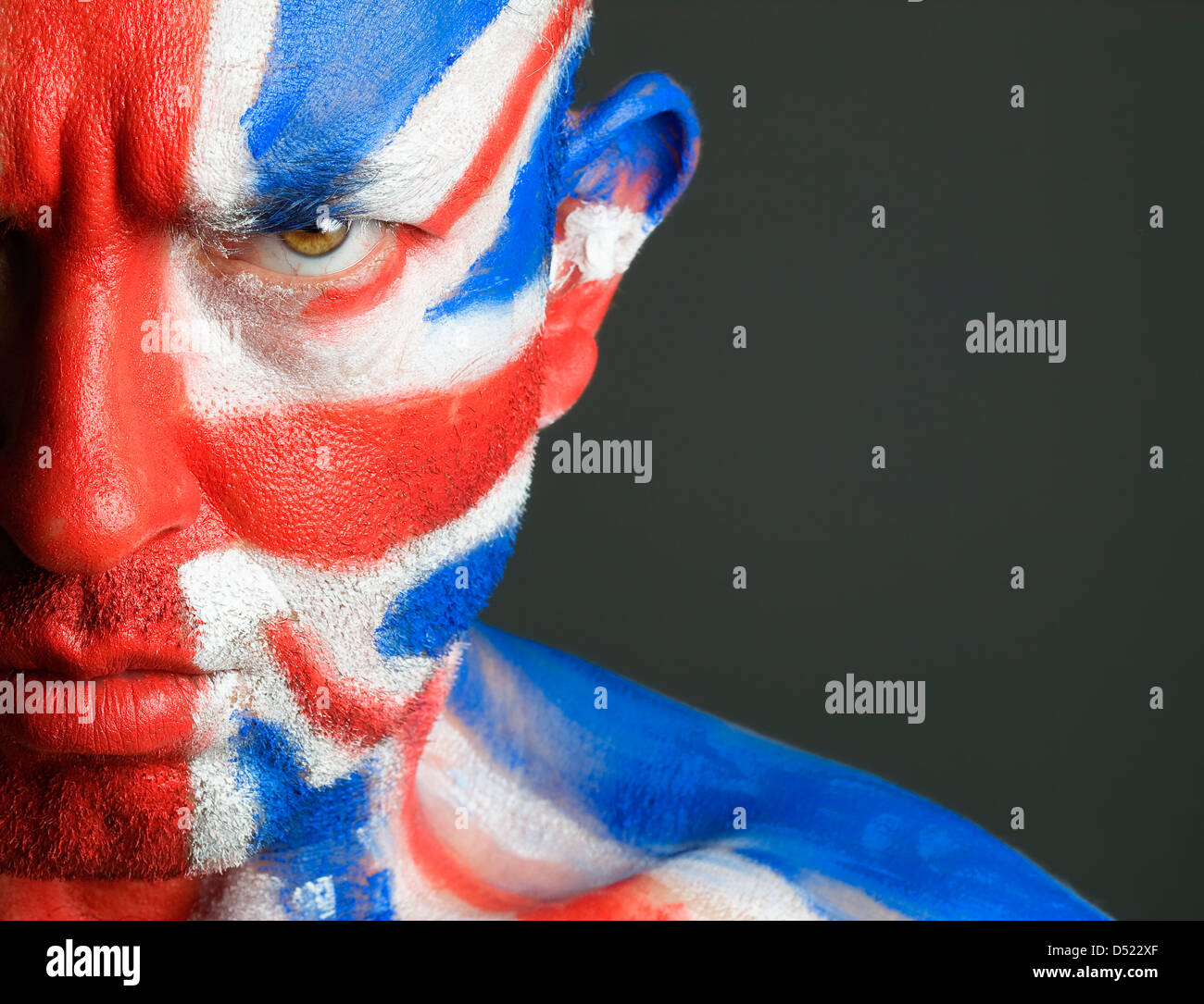 Man with his face painted with the flag of United Kingdom. The man is serious and photographic composition leaves only half of t Stock Photo
