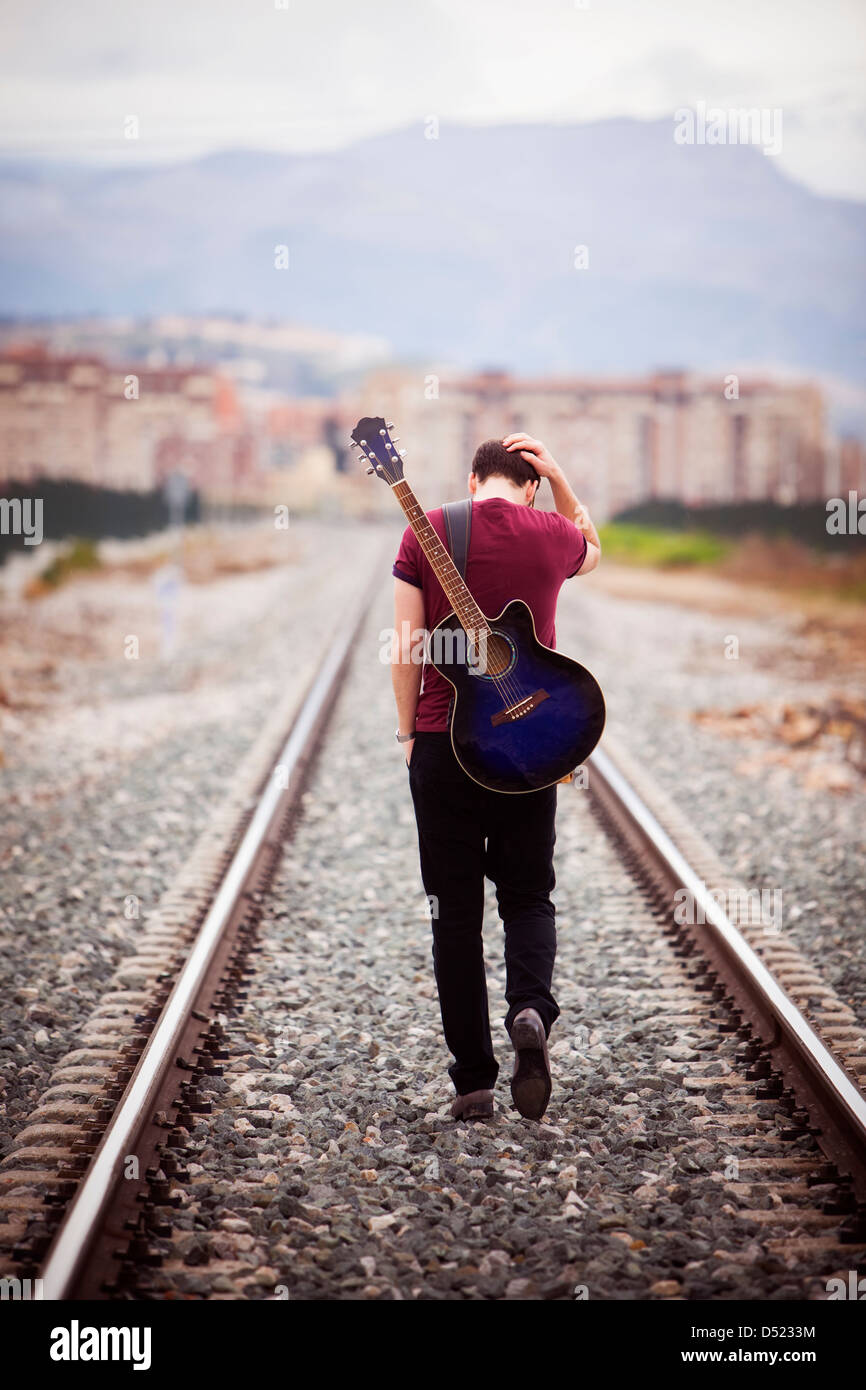Young male musician walking with his acustic guitar. Stock Photo