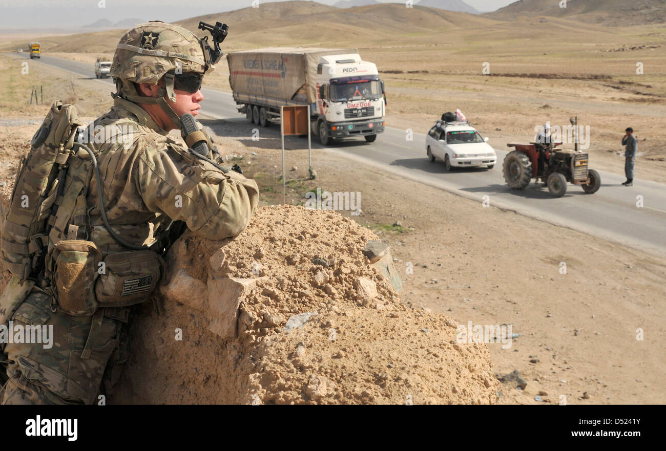 A US Army soldier keeps watch over an Afghan Uniform Police traffic control point along a highway February 28, 2013 in Kandahar Province, Afghanistan. Stock Photo