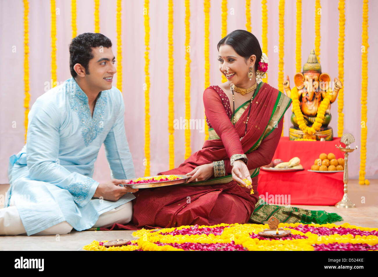 Maharashtrian couple making flower rangoli during ganesh chaturthi festival Stock Photo