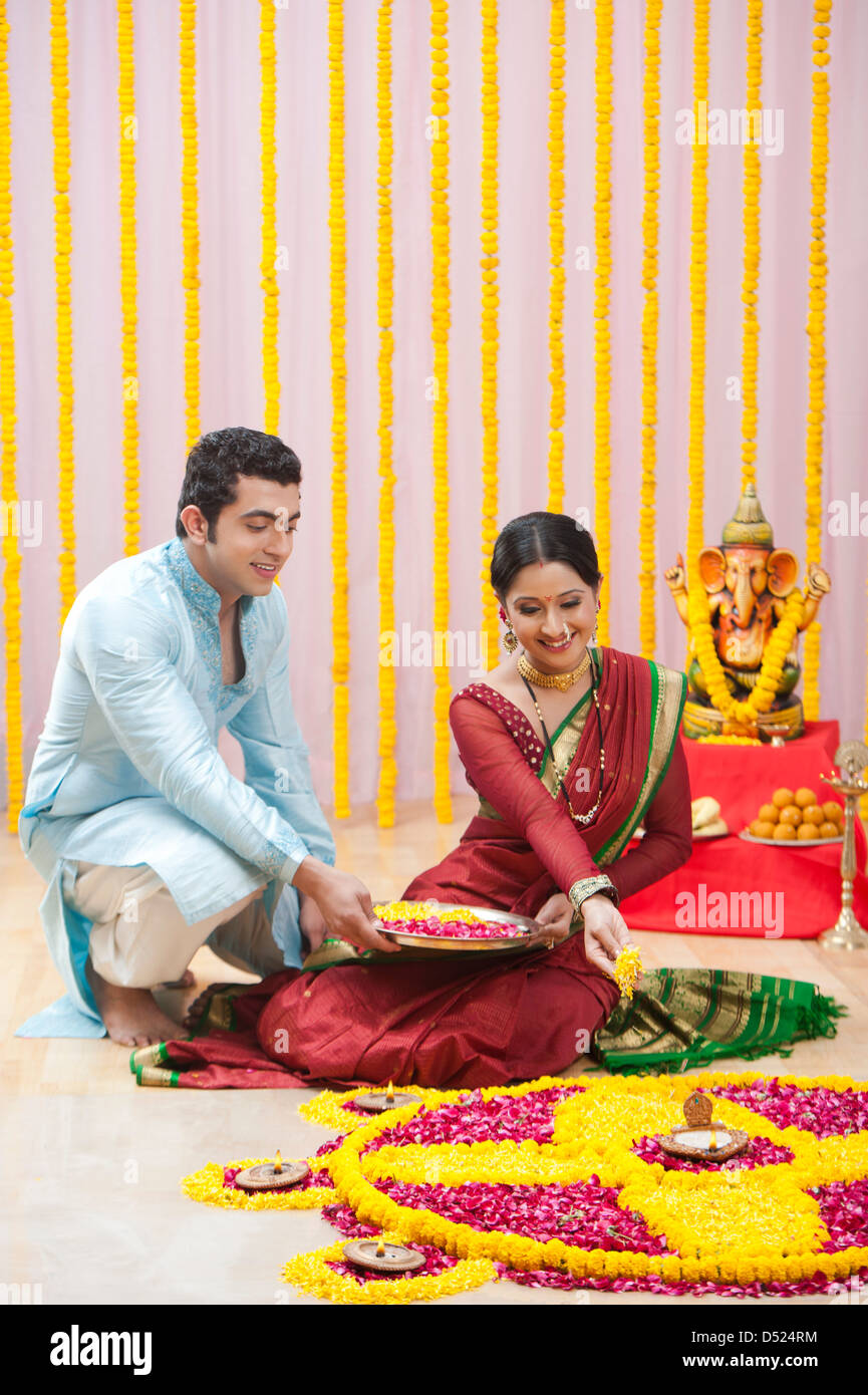 Maharashtrian couple making flower rangoli during ganesh chaturthi