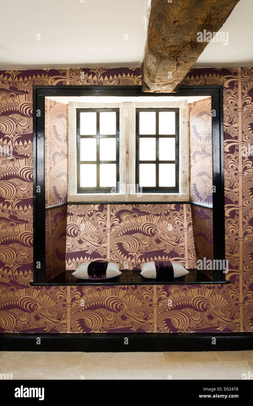 An unusual contemporary highly decorative wallpapered window seat in a period house. Stock Photo