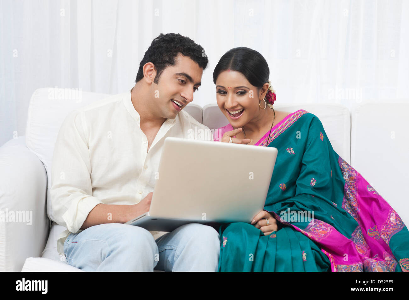 Couple using a laptop and smiling Stock Photo - Alamy