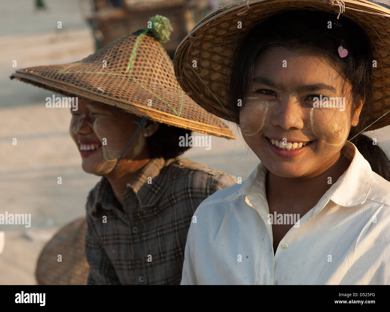 This young Burmese woman has, as is common, rubbed paste from thanaka bark on her face to protect it from the fierce sun. Stock Photo
