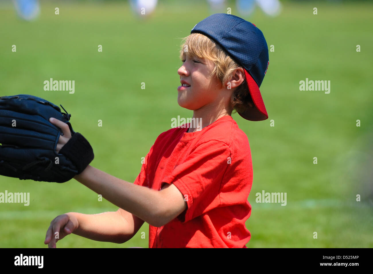 Young boy catching a baseball wearing hat backwards Stock Photo Alamy