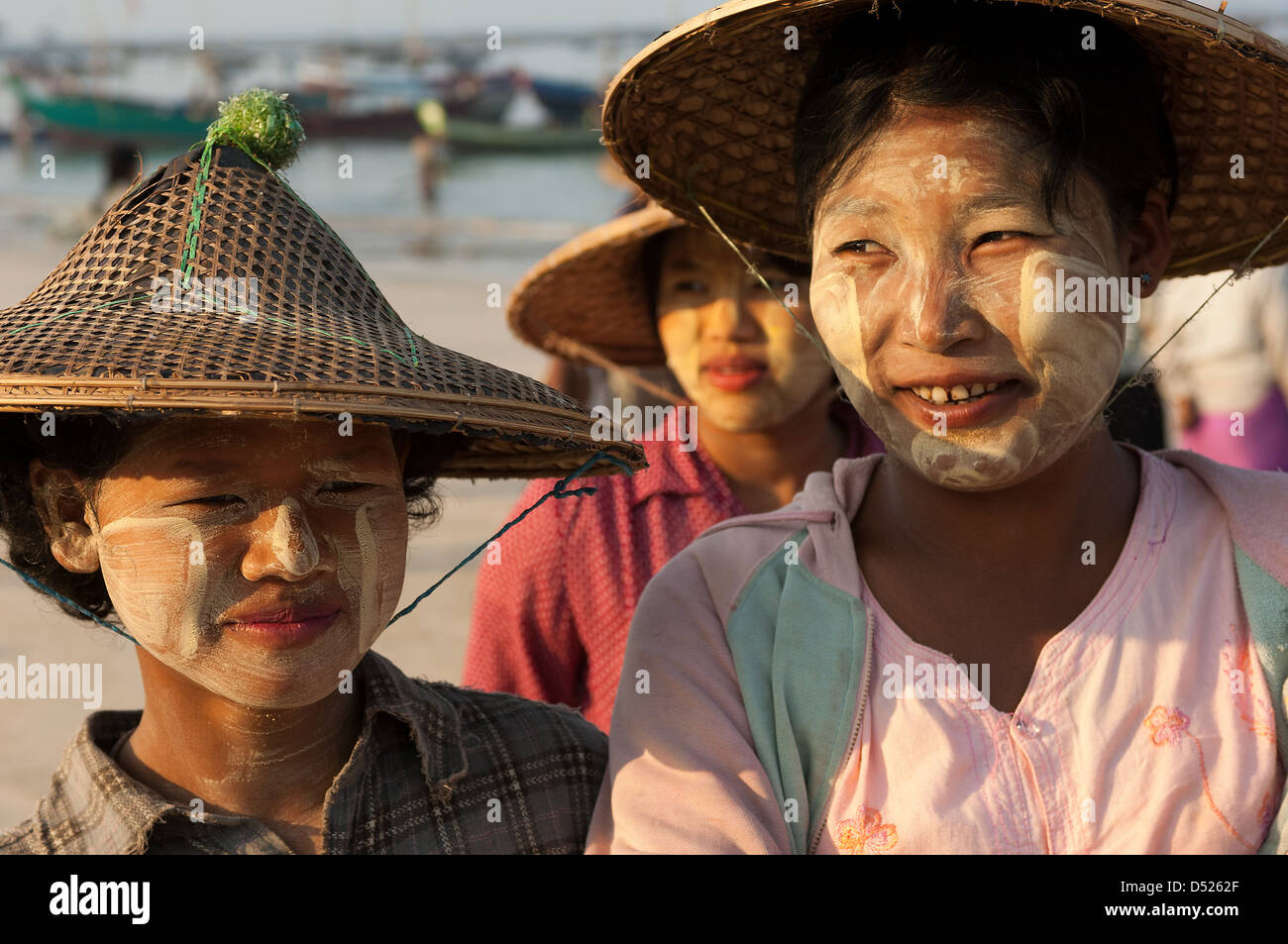 These young Burmese women have, as is common, rubbed paste from thanaka bark on their faces to protect them from the fierce sun. Stock Photo