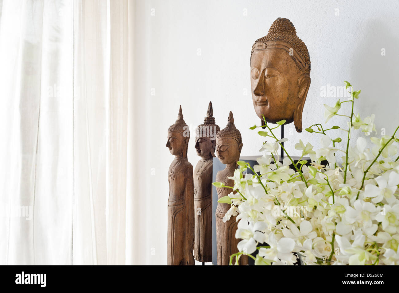 Buddha head and figurine in front of a white wall Stock Photo - Alamy