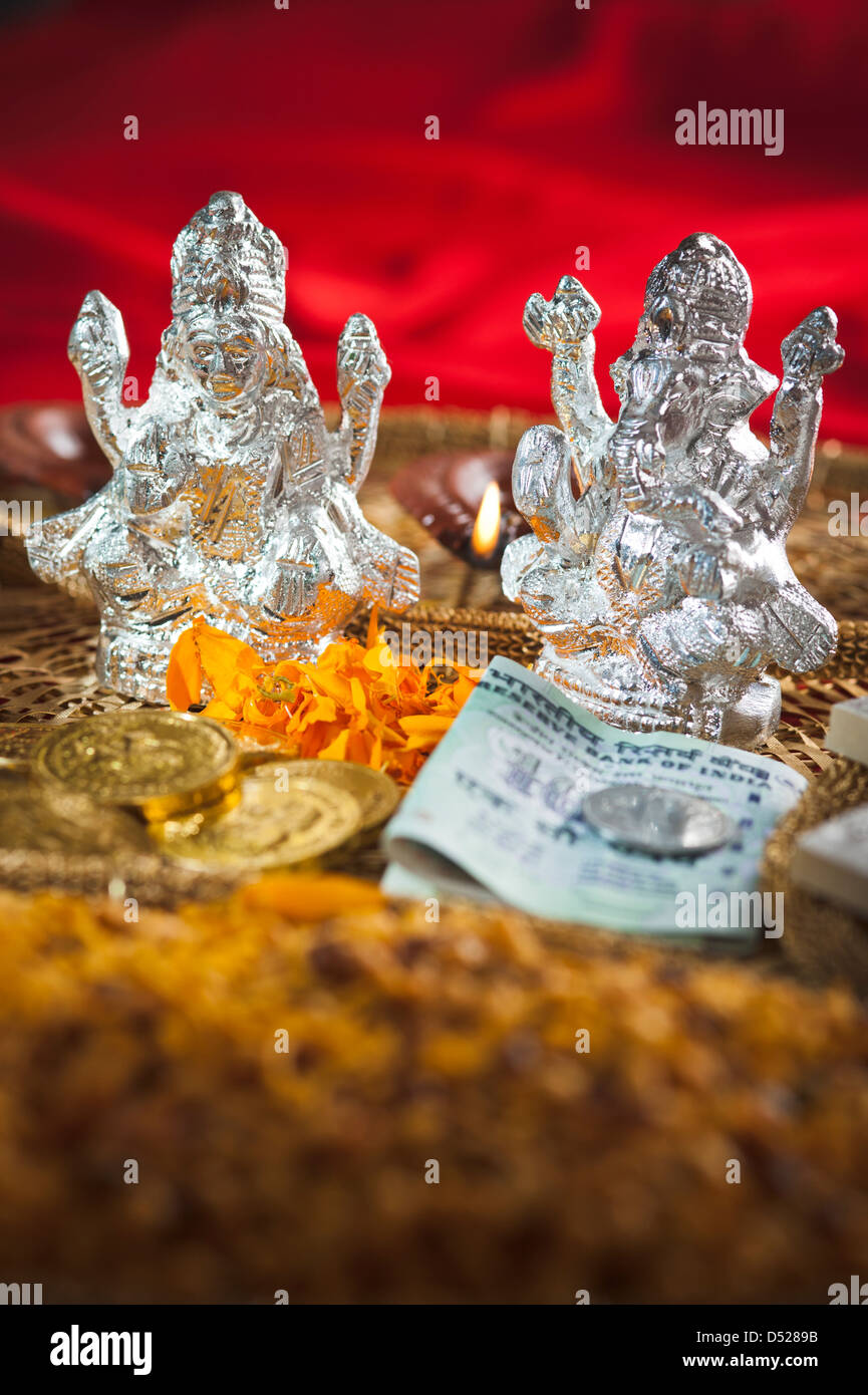 Snacks and money in front of idols of Lakshmi and Ganesh during Diwali festival Stock Photo