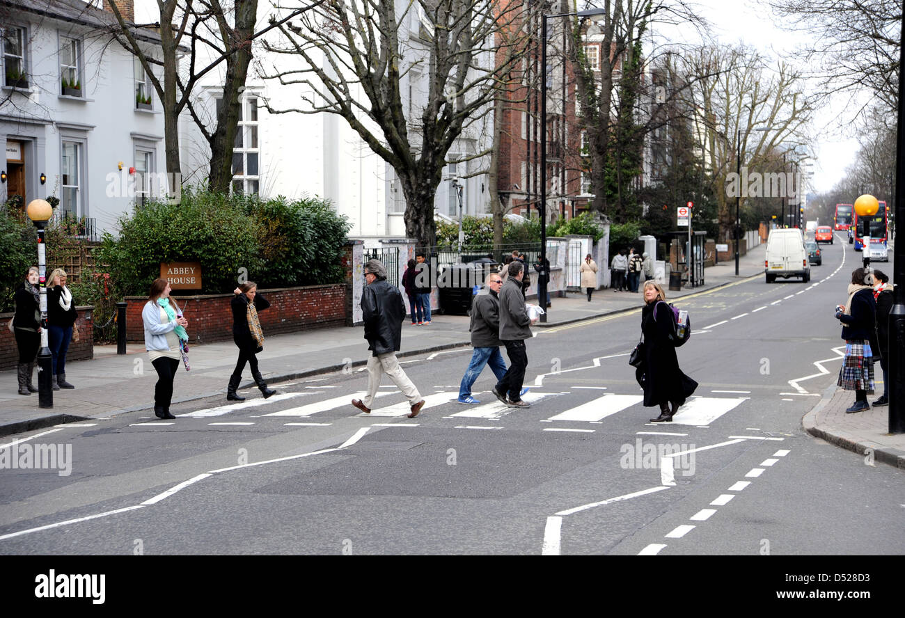 Tourists walk across the famous pedestrian zebra crossing in Abbey Road