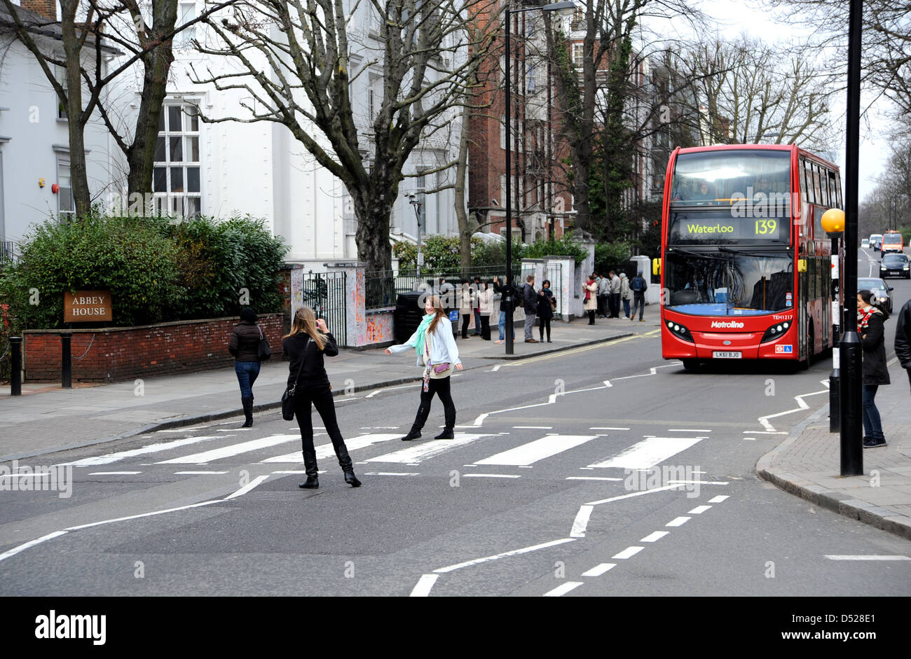 Tourists walk across the famous pedestrian zebra crossing in Abbey Road