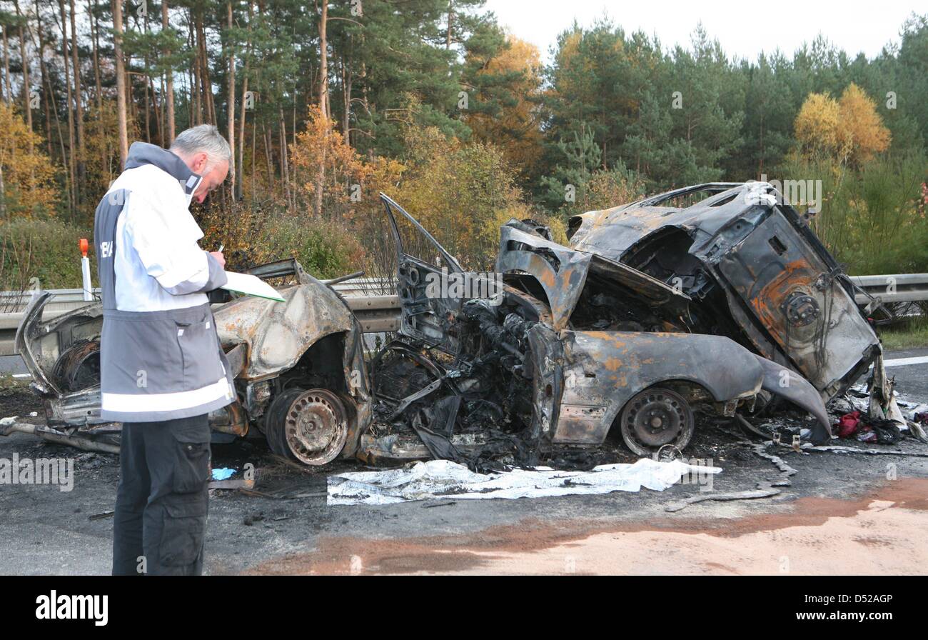 A policemen examines burntout vehicles after a severe car crash south
