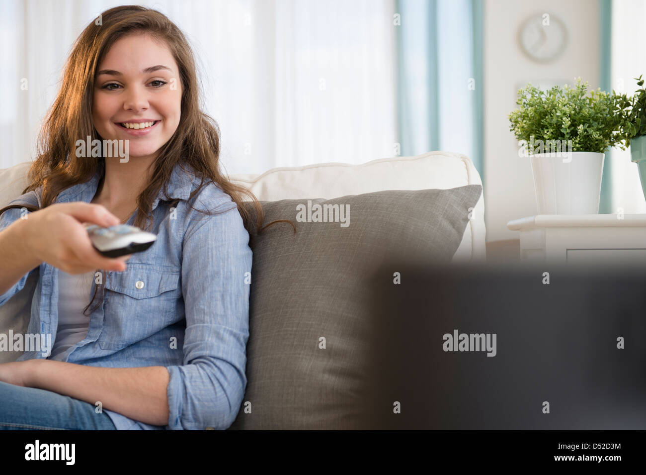 Hispanic girl watching television on sofa Stock Photo