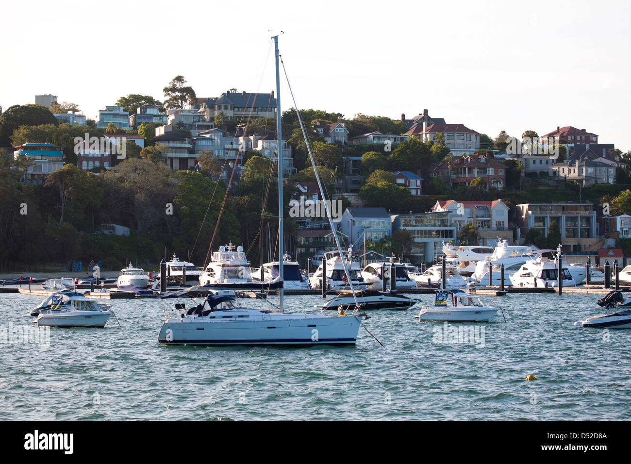 Moored pleasure boats and luxury yachts in front of waterfront houses at Rose Bay Sydney Australia Stock Photo