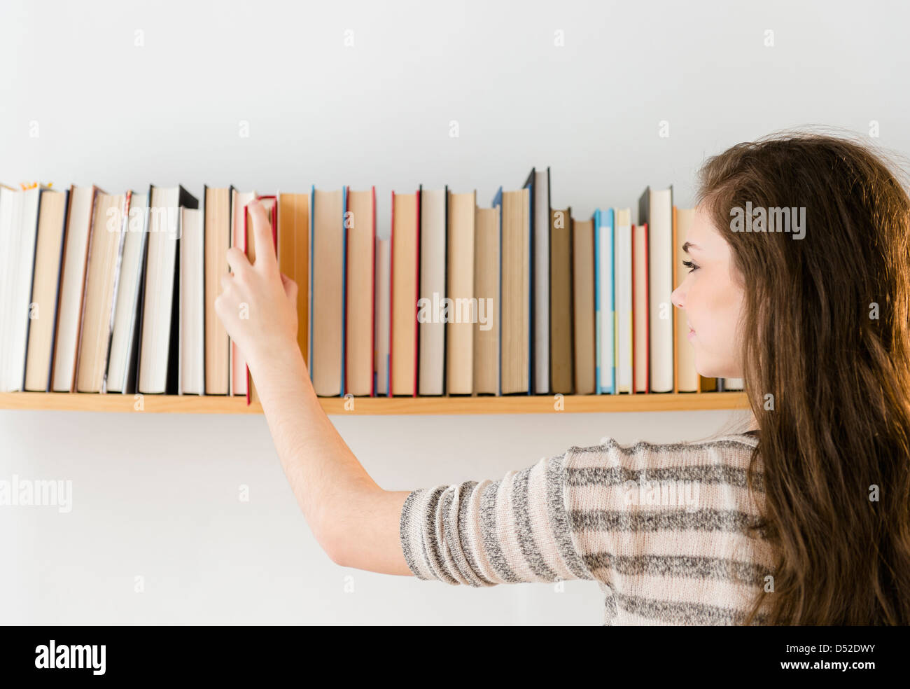Hispanic girl selecting book from shelf Stock Photo