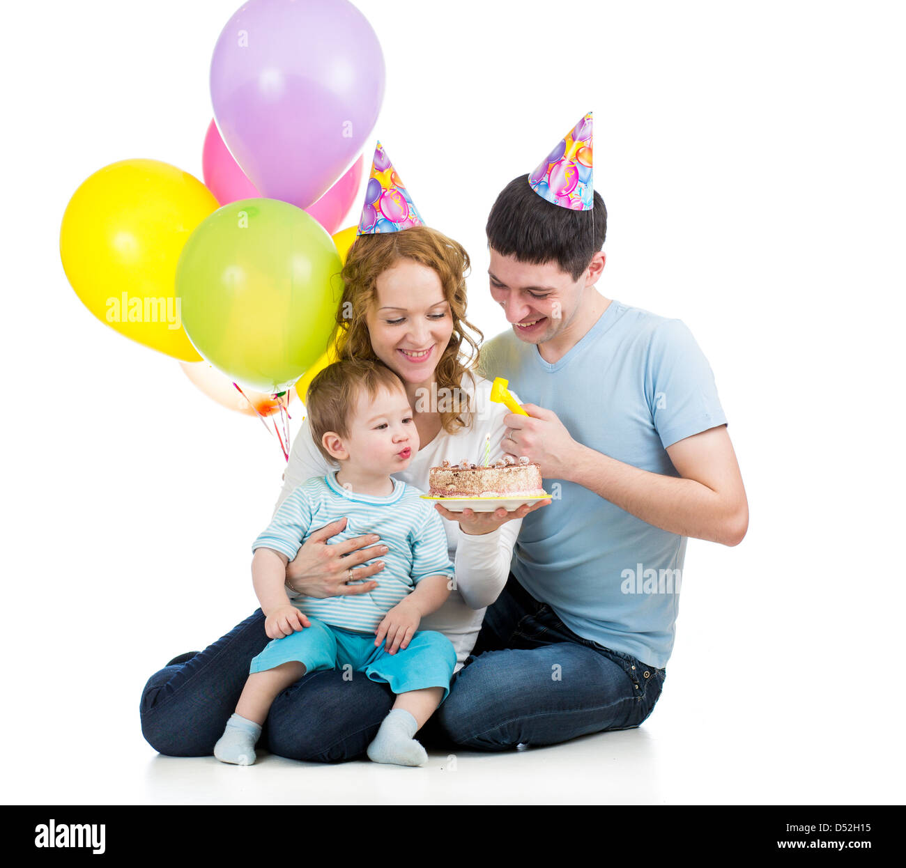 child boy with parents celebrating birthday and blowing candles on cake Stock Photo