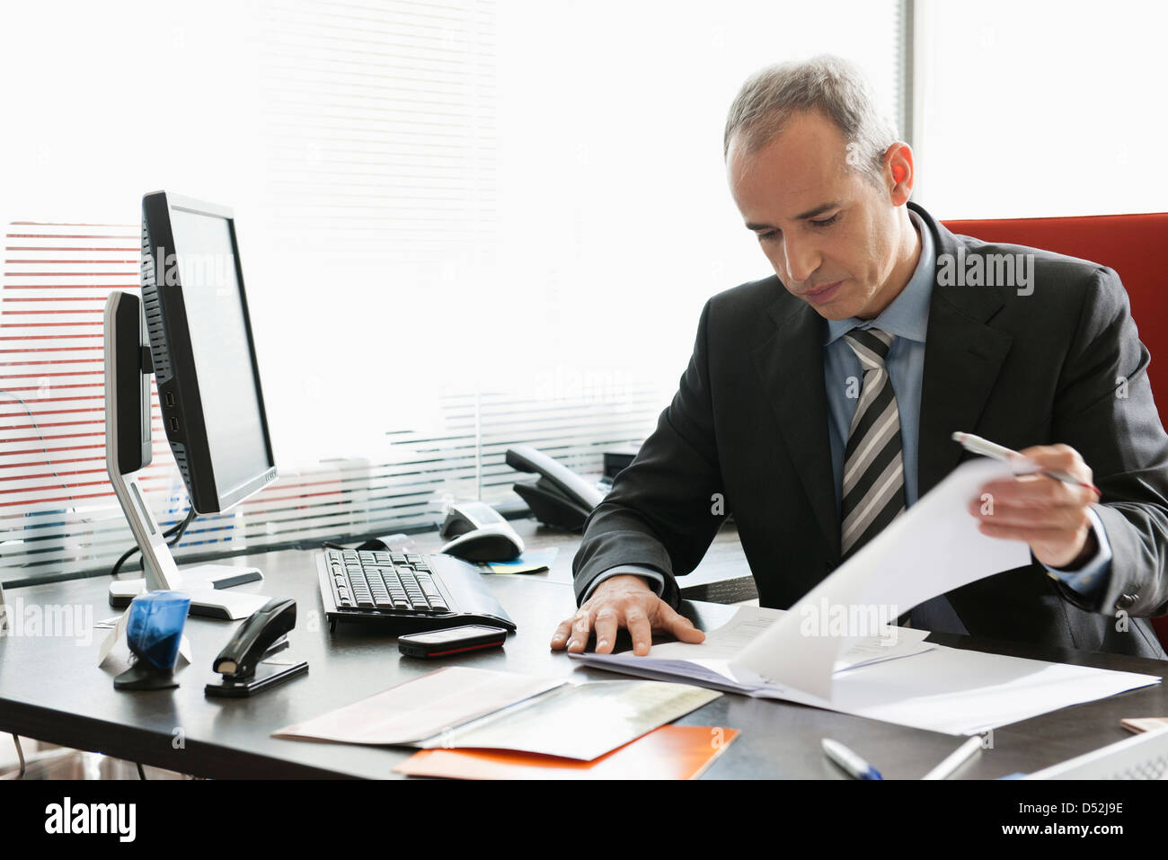 Business executive reviewing documents in office Stock Photo - Alamy