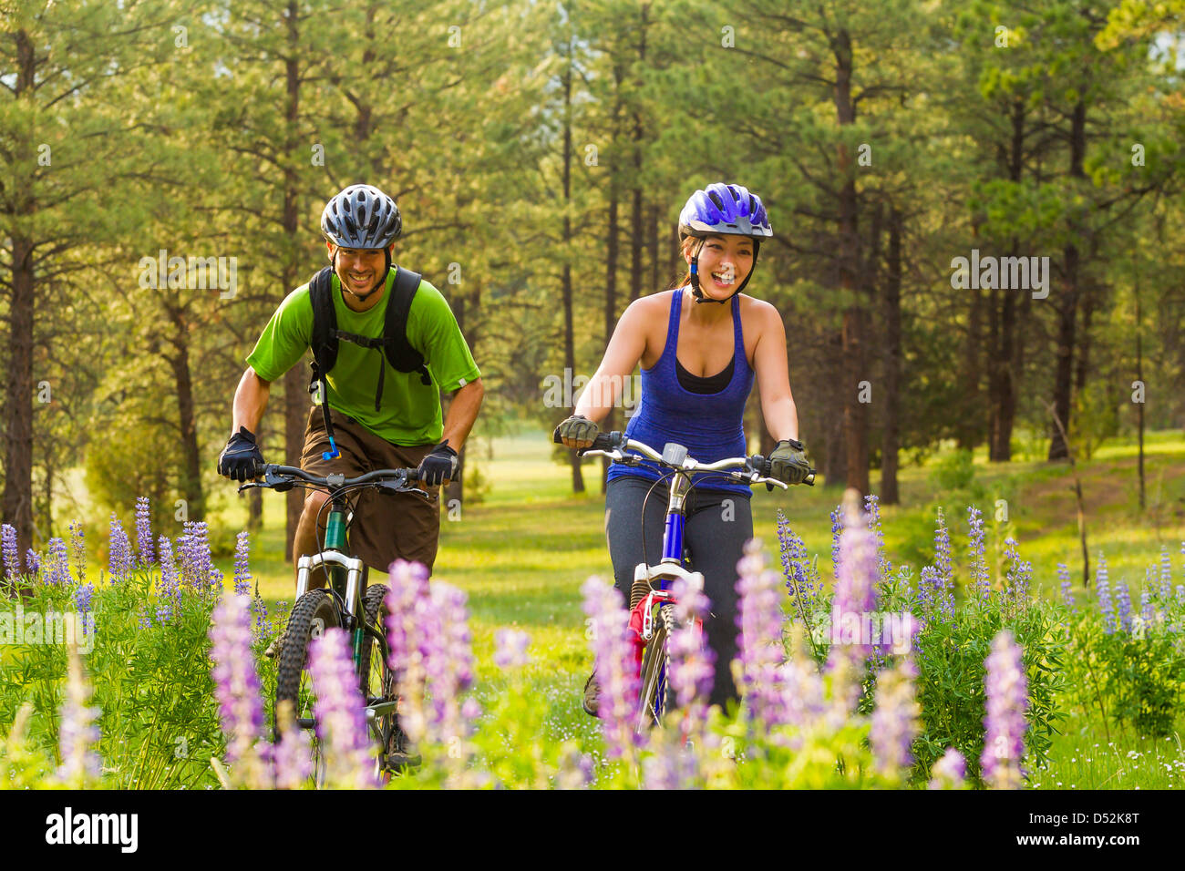 Couple riding mountain bikes in meadow Stock Photo Alamy