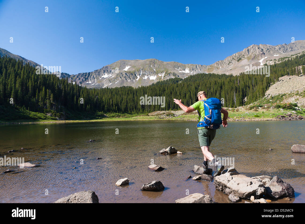 Caucasian hiker climbing on rocks in lake Stock Photo - Alamy