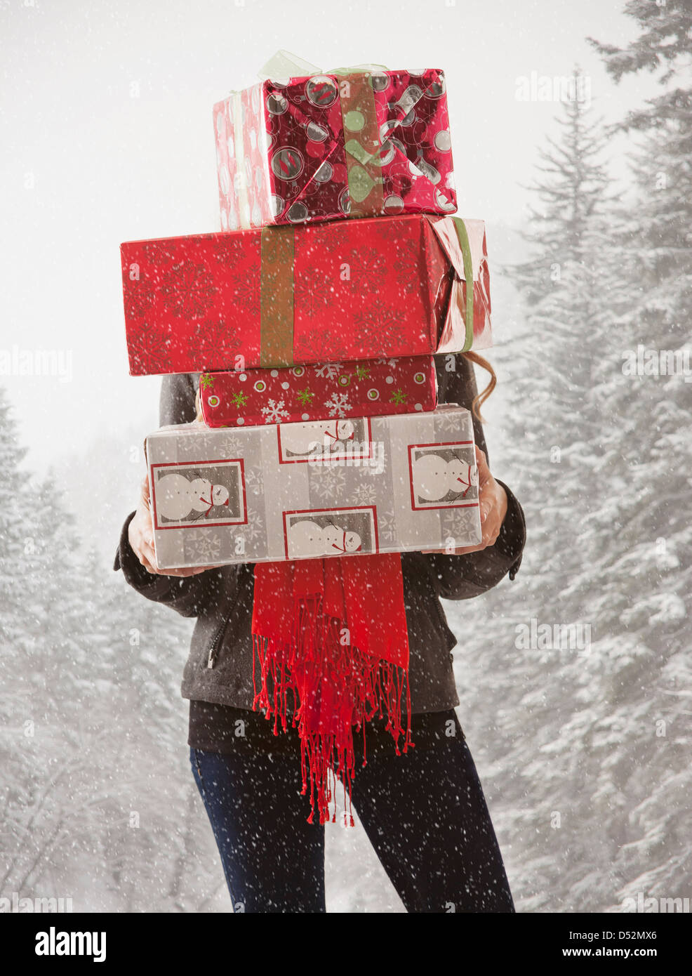 Mixed race woman holding stack of presents in snow Stock Photo