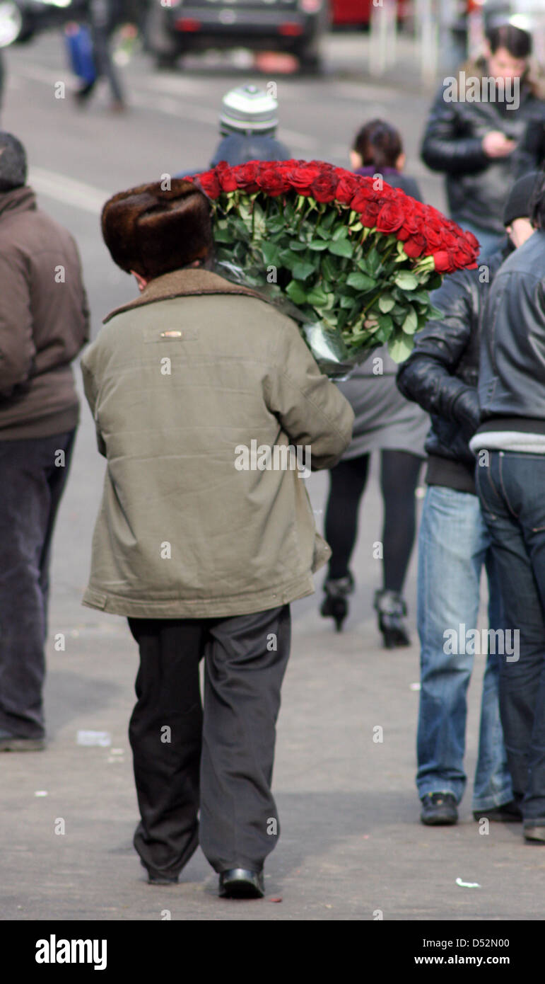 A man carries a large bouquet of white roses passed the Kiew train station in Moscow, Russia, 07 March 2010. During the days previous to the International Women's Day on 08 March, the florists hope for the business of the year: Prices reach from around 1000 rubel (25 euros) for a flowergreeting until 200000 Rubel (5000 euros) for a 60 kilogramm bouquet of 1001 roses. Photo: Ulf Mau Stock Photo