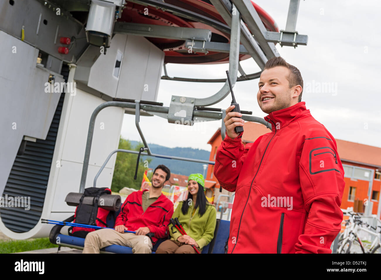 Man in red coat using radio starting chair lift Stock Photo Alamy