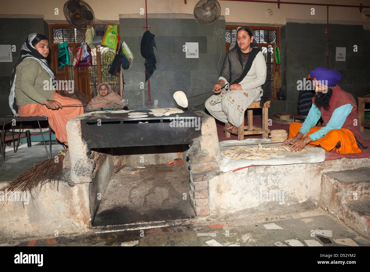 Volunteers cooking chapattis inside the kitchens of the Golden Temple complex in Amritsar, Punjab, India. Stock Photo