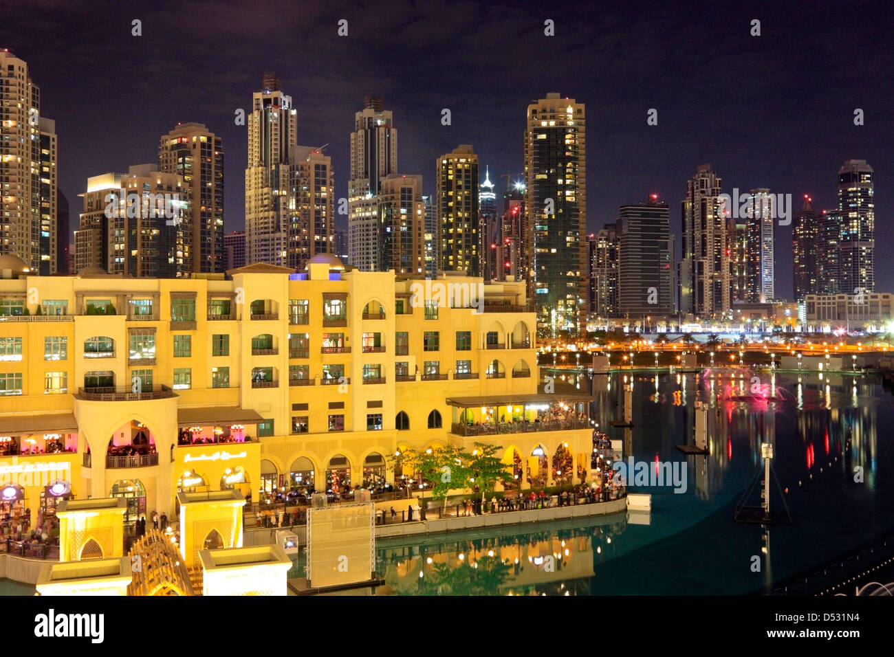 Souk al Bahar and the Skyline of Dubai Downtown, seen across the fountain lake at night, United Arab Emirates Stock Photo