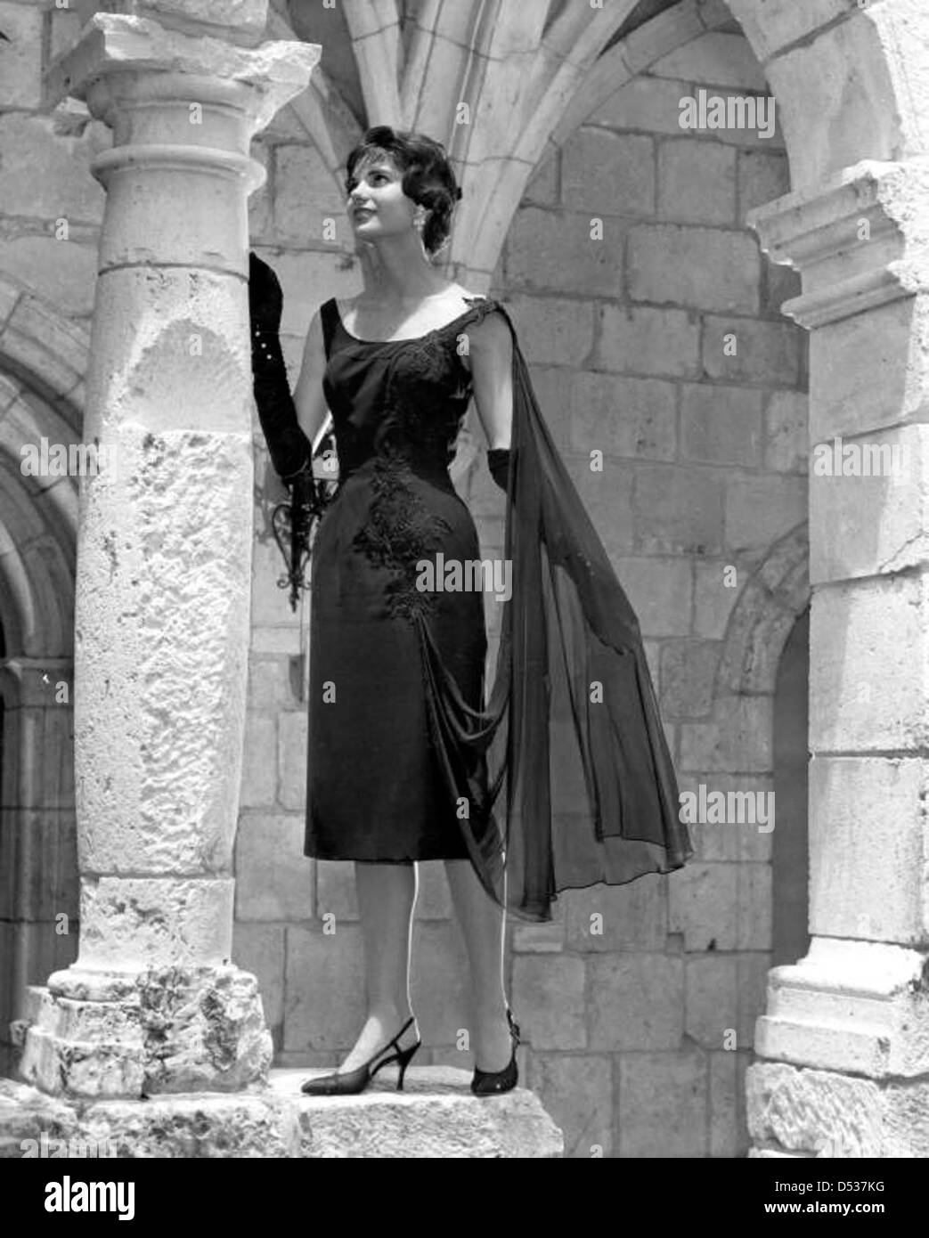A fashion model in dress poses by column at Ancient Spanish Monastery: North Miami Beach, Florida Stock Photo