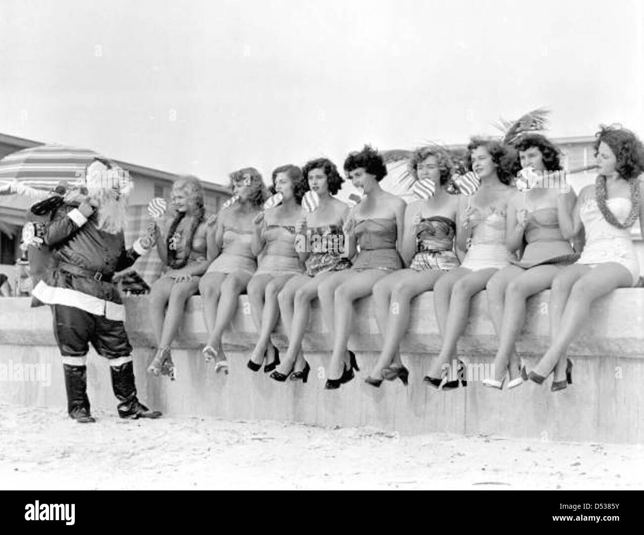 Santa Claus handing out treats to nine young women on the beach: Saint Petersburg, Florida Stock Photo