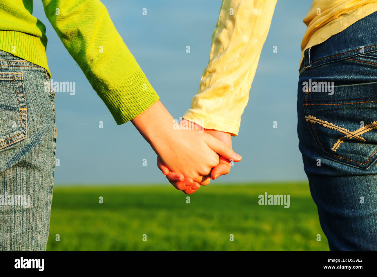 Teen girls holding hands against blue sky Stock Photo - Alamy