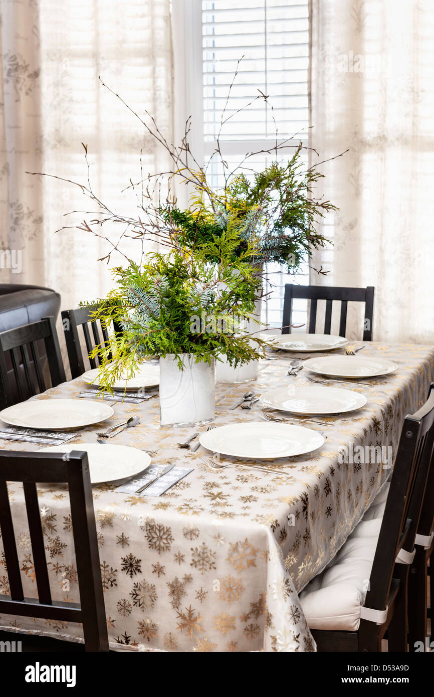 Dining table decorated for Christmas with eight place settings and evergreen centerpiece Stock Photo