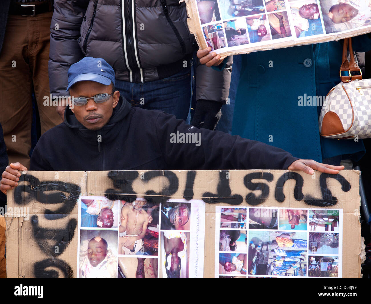 Protester against dictator Alpha Conde of Guinea with upside down sign with pictures of tortured victims. Brussels, Belgium Stock Photo