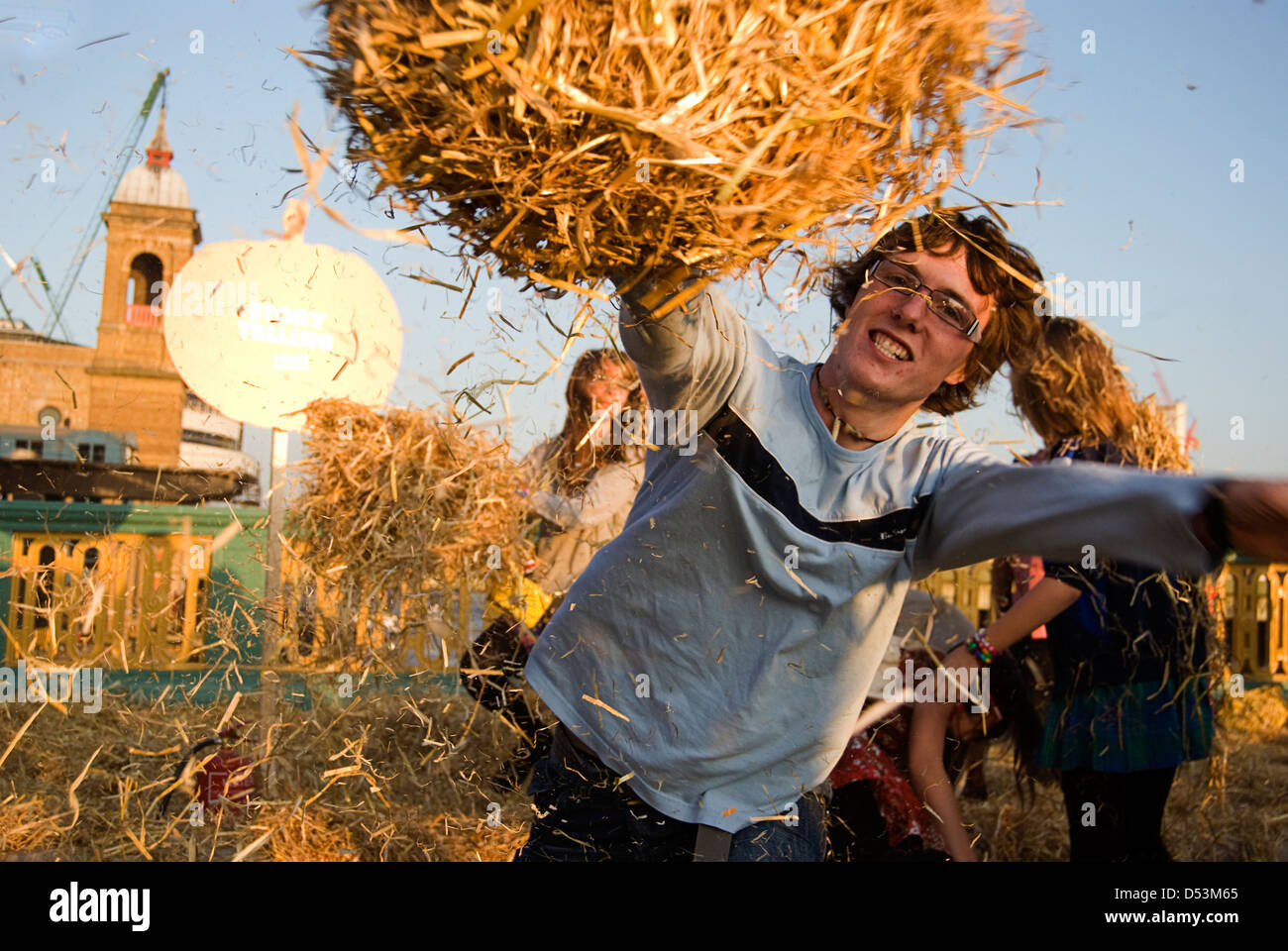 Boy throwing hay in a play fight on Southwark Bridge during the Thames