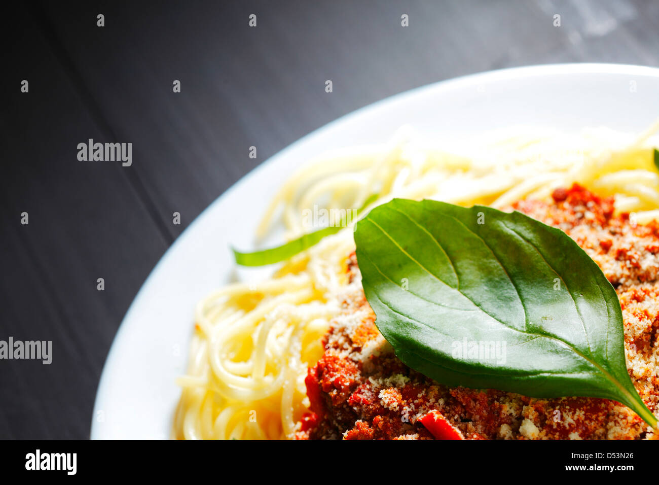 Spaghetti bolognese with basil in white plate on black table Stock