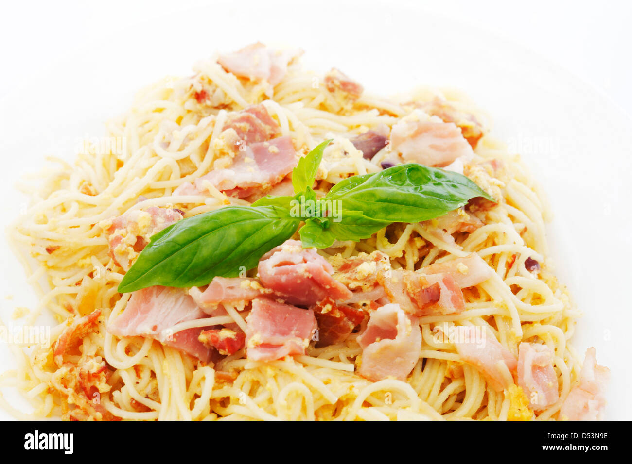 Spaghetti carbonara with fried bacon and basil isolated on white Stock