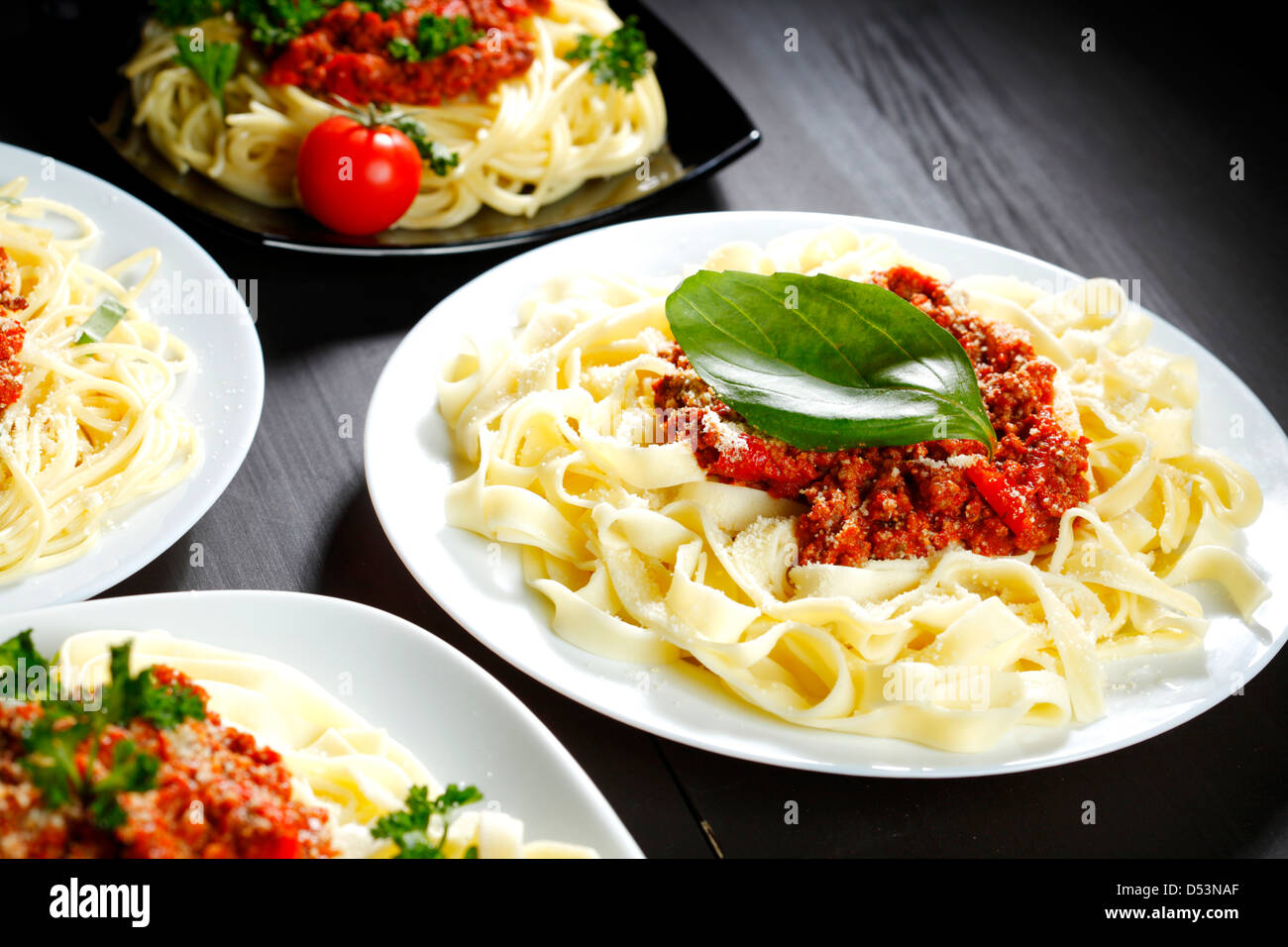 Spaghetti bolognese with basil in white plates on black table Stock Photo Alamy
