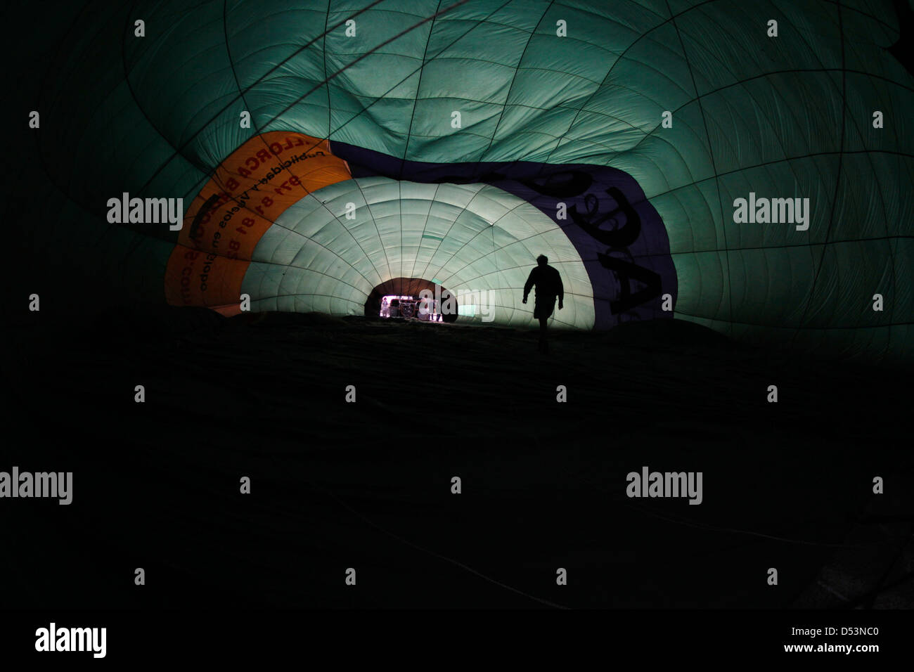 A crew member checks the inside of a hot air balloon envelope before start to heat the air and lifting. Stock Photo