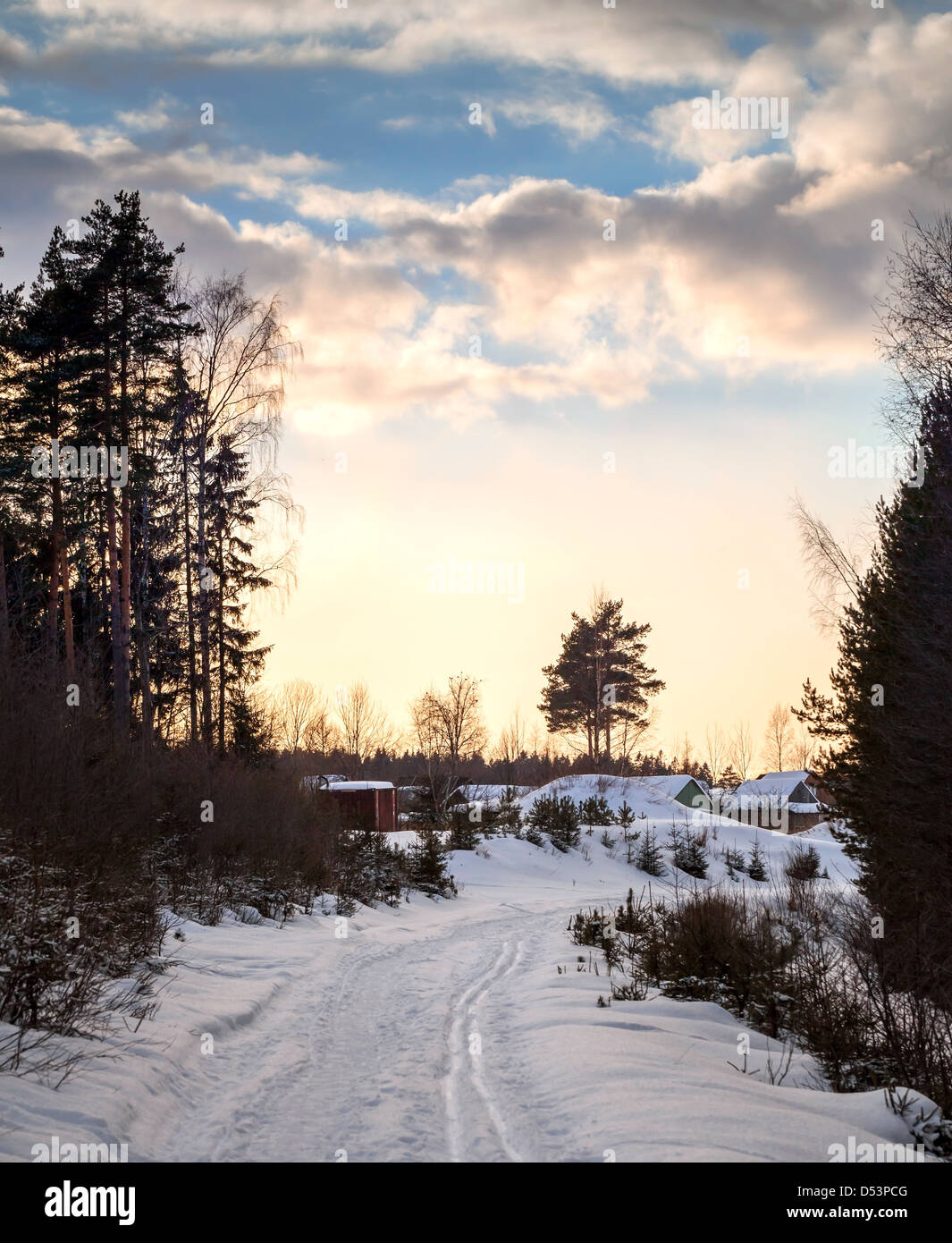 Snowy road in cold winter village under evening cloudy sky. Karelia, Russia Stock Photo