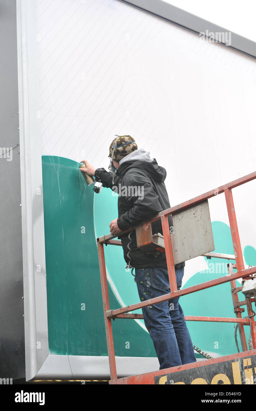 Old Street, London, UK. 24th March 2013. An artist spraypaints onto one of the billboards in Old Street as part of the CALM campaign. Graffiti artists paint on three billboards in Old Street, London for CALM (Campaign Against Living Miserably) to highlight the issue that on average three young men end their lives everyday due to depression and anxiety. Stock Photo