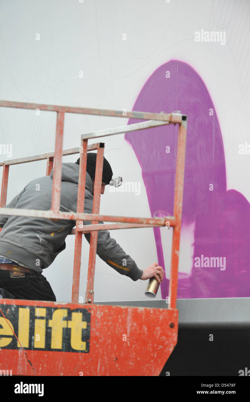 Old Street, London, UK. 24th March 2013. An artist spraypaints onto one of the billboards in Old Street as part of the CALM campaign. Graffiti artists paint on three billboards in Old Street, London for CALM (Campaign Against Living Miserably) to highlight the issue that on average three young men end their lives everyday due to depression and anxiety. Stock Photo