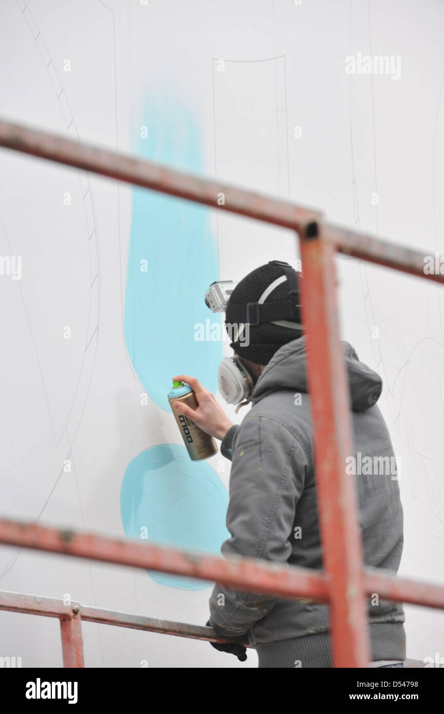 Old Street, London, UK. 24th March 2013. An artist spraypaints onto one of the billboards in Old Street as part of the CALM campaign. Graffiti artists paint on three billboards in Old Street, London for CALM (Campaign Against Living Miserably) to highlight the issue that on average three young men end their lives everyday due to depression and anxiety. Stock Photo