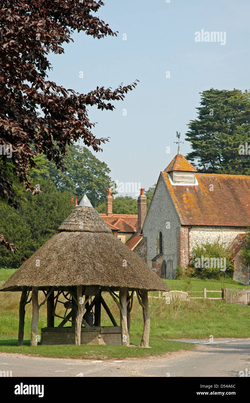 St. Peter's Church ( thirteenth century) and the thatched well head. East Marden, West Sussex. Stock Photo