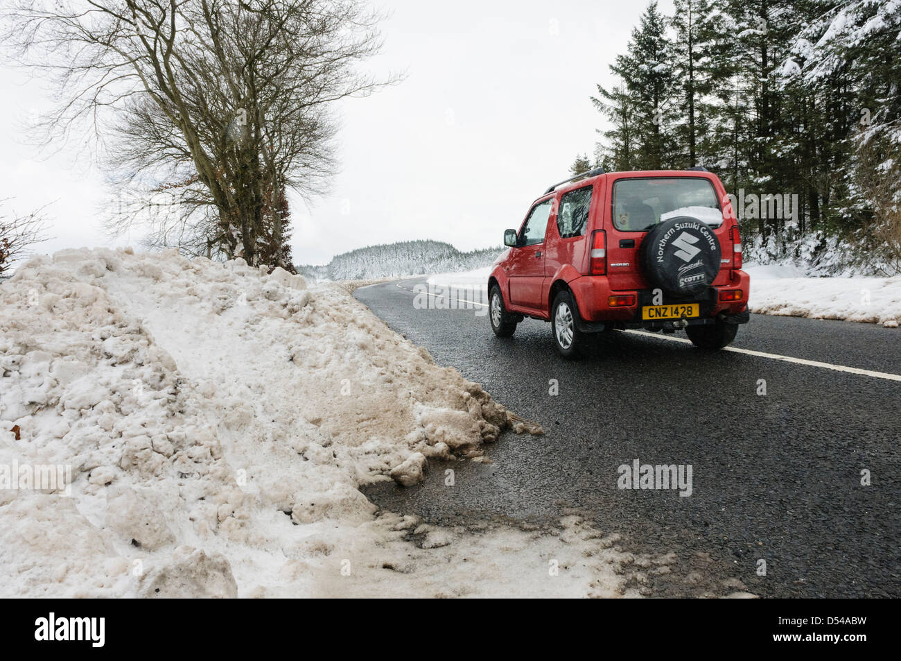 A 4x4 drives along a road which has been recently cleared of snow Stock Photo