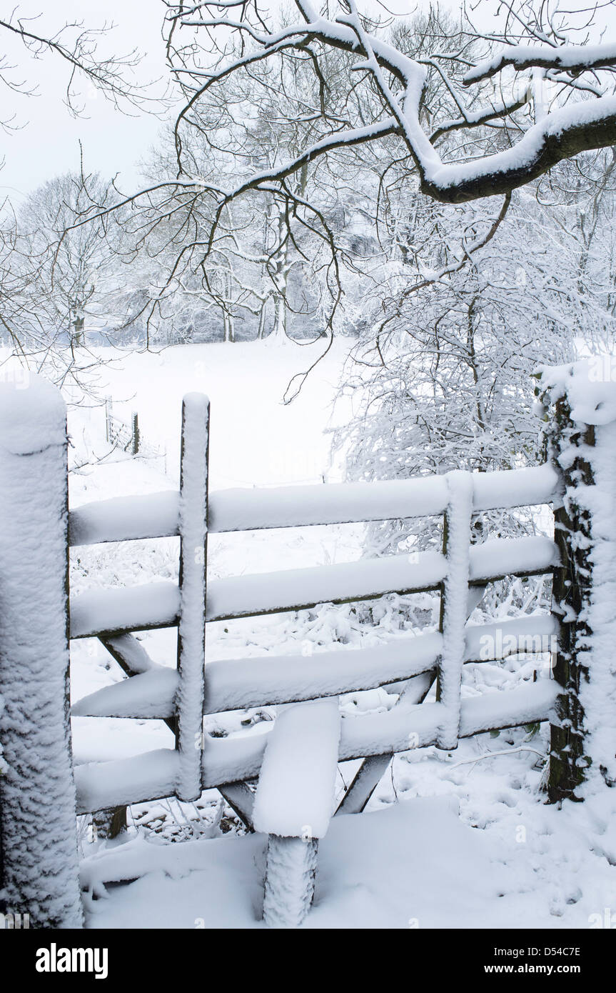 Footpath Stile covered in winter snow the Cotswolds, Gloucestershire, England, UK Stock Photo