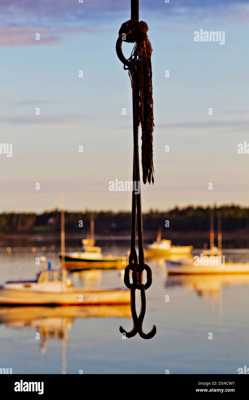 A silhouette of a hook in front of lobster boats in the harbor at