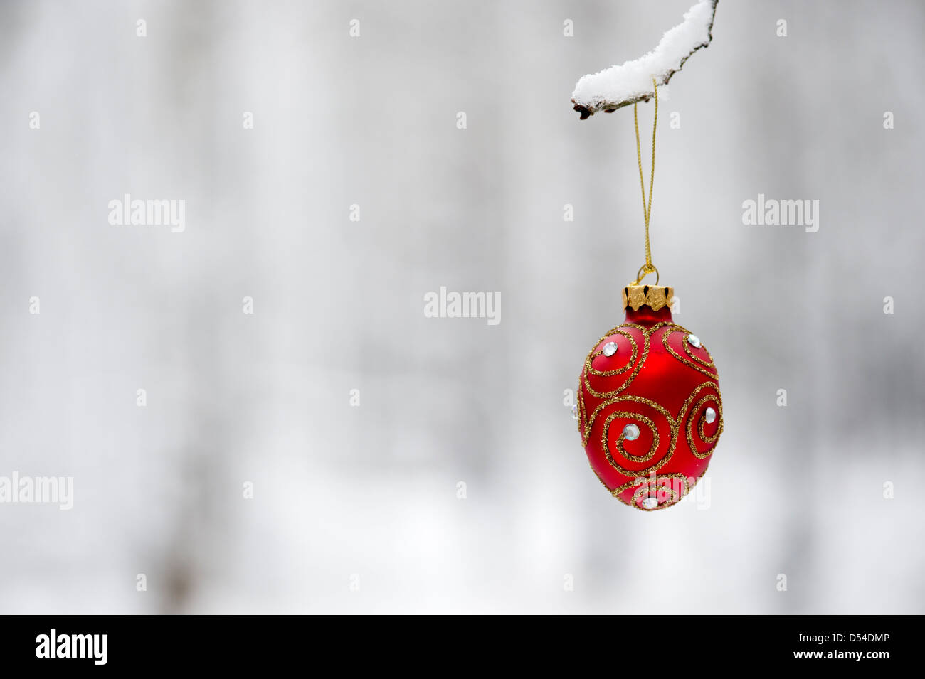 Christmas tree decorations / baubles hanging on a tree branch in the snow Stock Photo